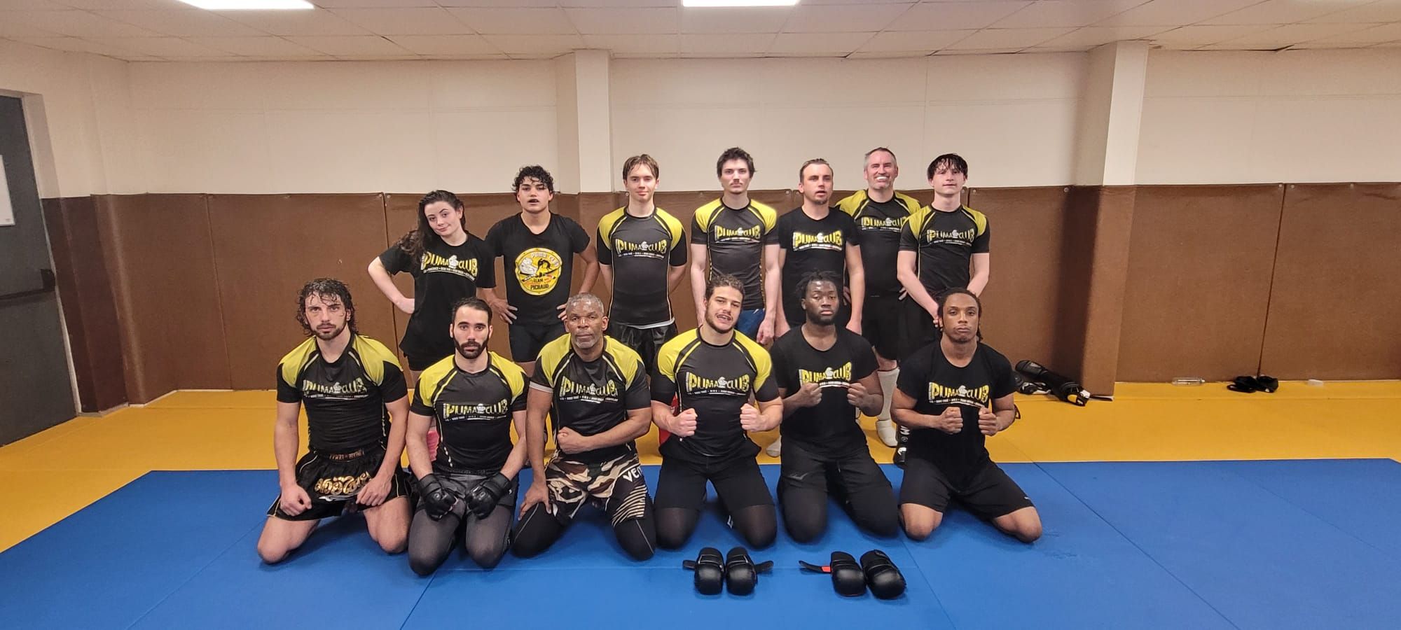 Groupe d'adultes du Puma Club à genoux sur le tatami, en t-shirt du club.